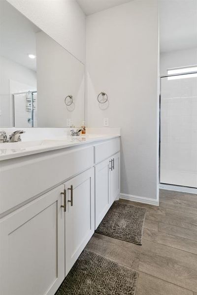 Full bathroom with double vanity, a stall shower, and light wood-type flooring