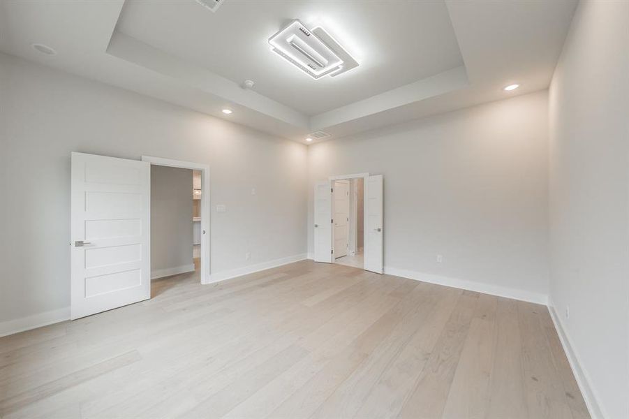 Unfurnished room featuring a tray ceiling, light wood-type flooring, recessed lighting, and cooling unit