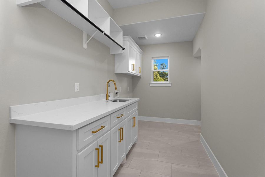 Spacious laundry room with upper cabinets for added organization and convenience. Spacious laundry room with upper cabinets for added organization and convenience.