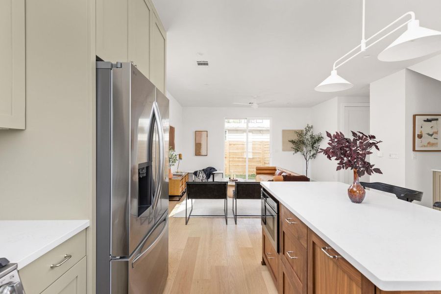Kitchen with stainless steel appliances, light wood-style floors, a center island, hanging light fixtures, and open floor plan