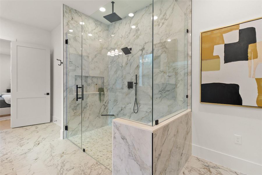 Every shower feels like a five-star experience in your expansive walk-in shower, wrapped in marble-look tile with dual rainfall showerheads and sleek frameless glass.