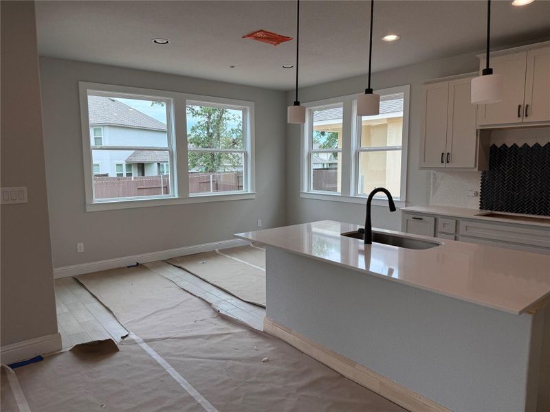 Kitchen featuring recessed lighting, light countertops, white cabinets, decorative light fixtures, and a kitchen island with sink Kitchen featuring recessed lighting, light countertops, white cabinets, decorative light fixtures, and a kitchen island with sink