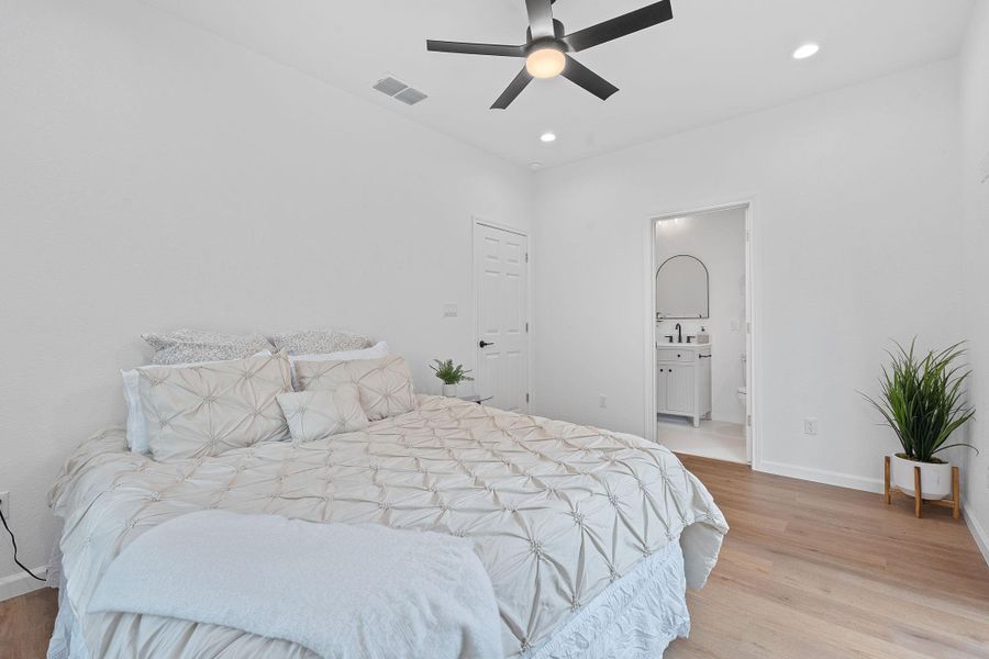 Bedroom with light wood-type flooring, recessed lighting, a ceiling fan, and ensuite bathroom