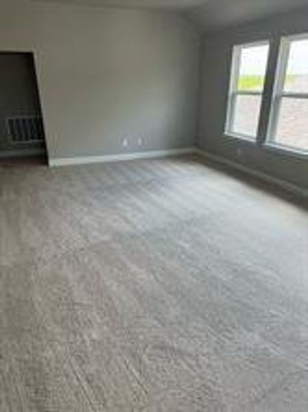 Empty room with light colored carpet and vaulted ceiling