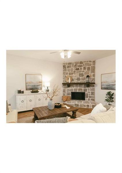 Living room with hardwood / wood-style flooring, ceiling fan, and a fireplace