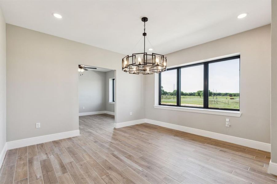 Separate dining area with recessed lighting, wood look tile floors, baseboards, big natural light windows and notable chandelier. Separate dining area with recessed lighting, wood look tile floors, baseboards, big natural light windows and notable chandelier.