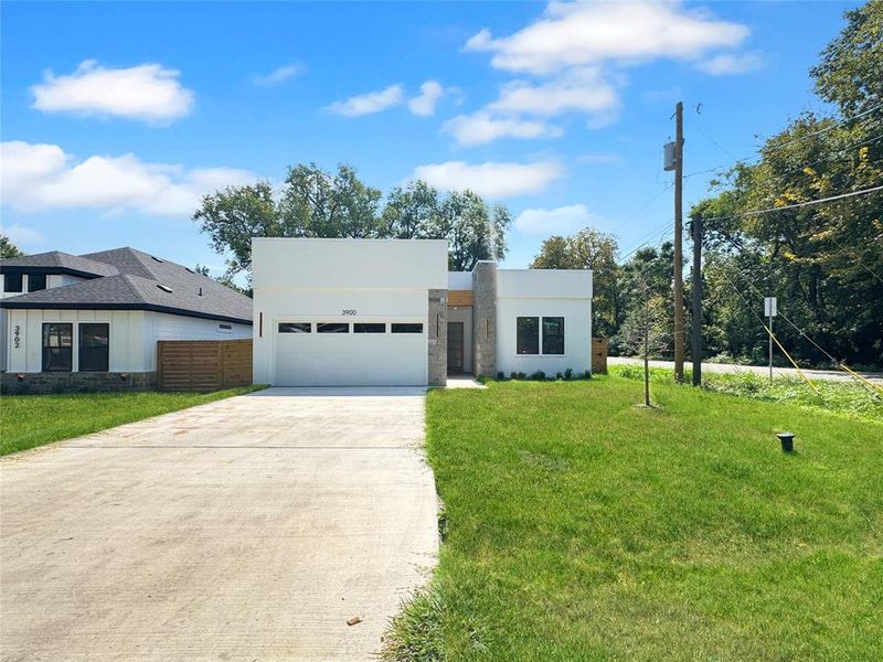 Contemporary home featuring a garage, a front lawn, concrete driveway, and stucco siding