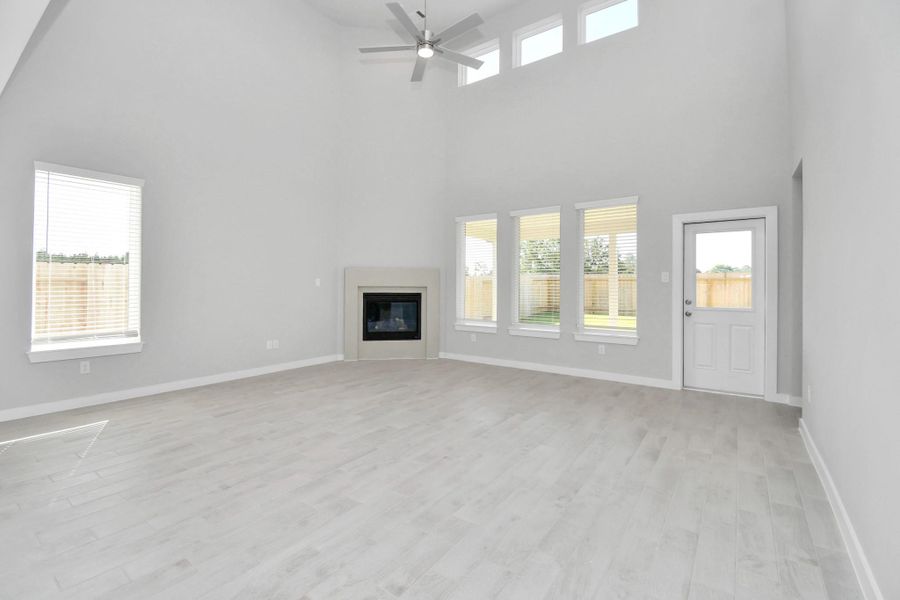 Welcome family and guests to your charming living room! With its high ceilings, recessed lighting, ceiling fan, custom paint, beautiful flooring, and large windows that let in abundant natural light, this room is perfect for gatherings. Sample photo of completed home with similar floor plan. Actual colors and selections may vary.