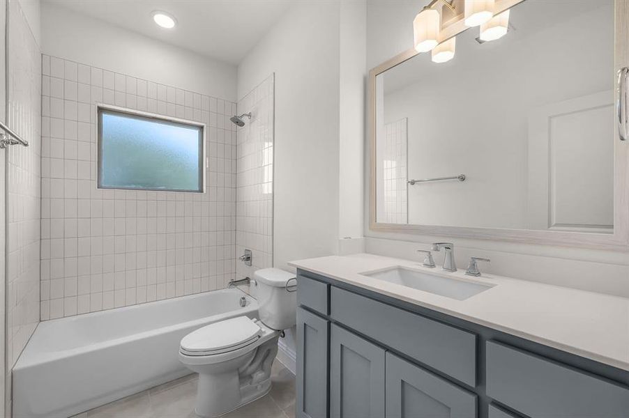 Bathroom featuring shower / bath combination, vanity, and light tile patterned floors