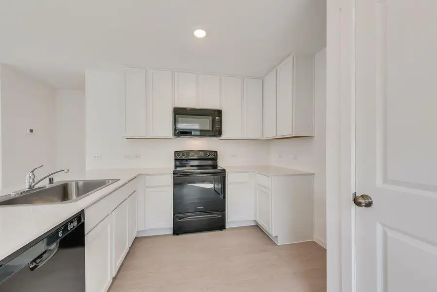 Kitchen with black appliances, white cabinets, light wood-style floors, recessed lighting, and a peninsula
