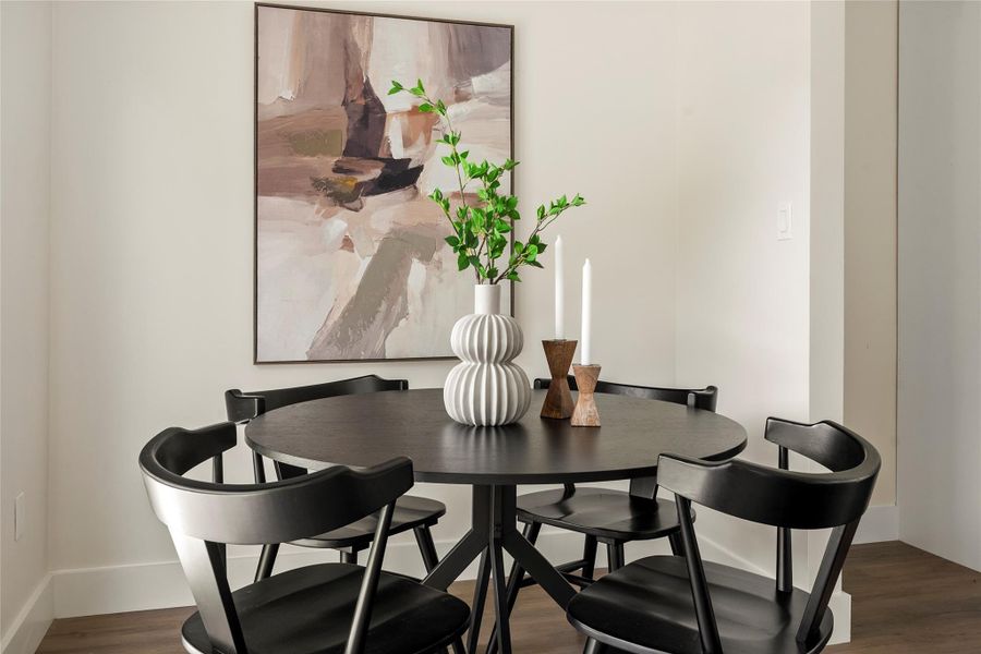 A dark, round dining table creates a refined centerpiece in this naturally illuminated dining area.