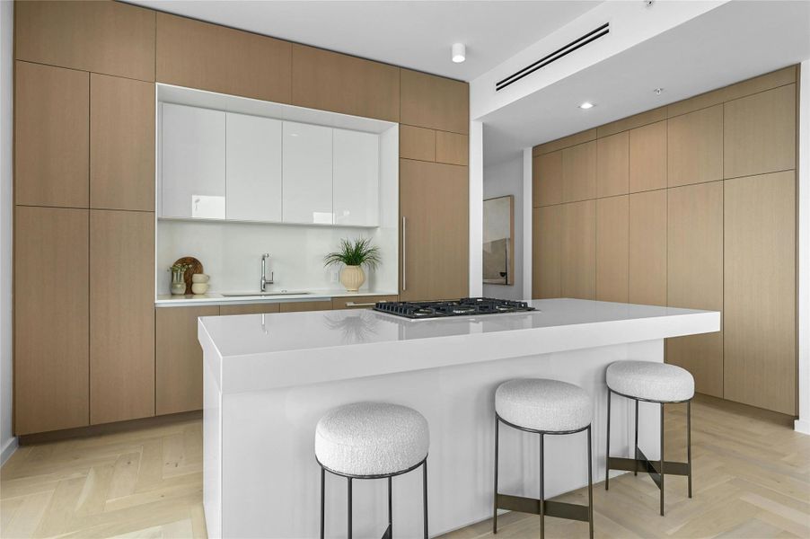Modern kitchen with custom cabinetry, integrated refrigerator, and a sleek island with gas cooktop. Modern kitchen with custom cabinetry, integrated refrigerator, and a sleek island with gas cooktop.