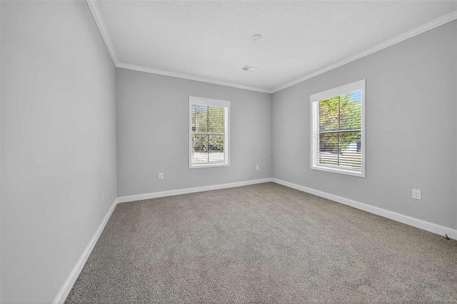 Empty room with ornamental molding, plenty of natural light, and light colored carpet Empty room with ornamental molding, plenty of natural light, and light colored carpet
