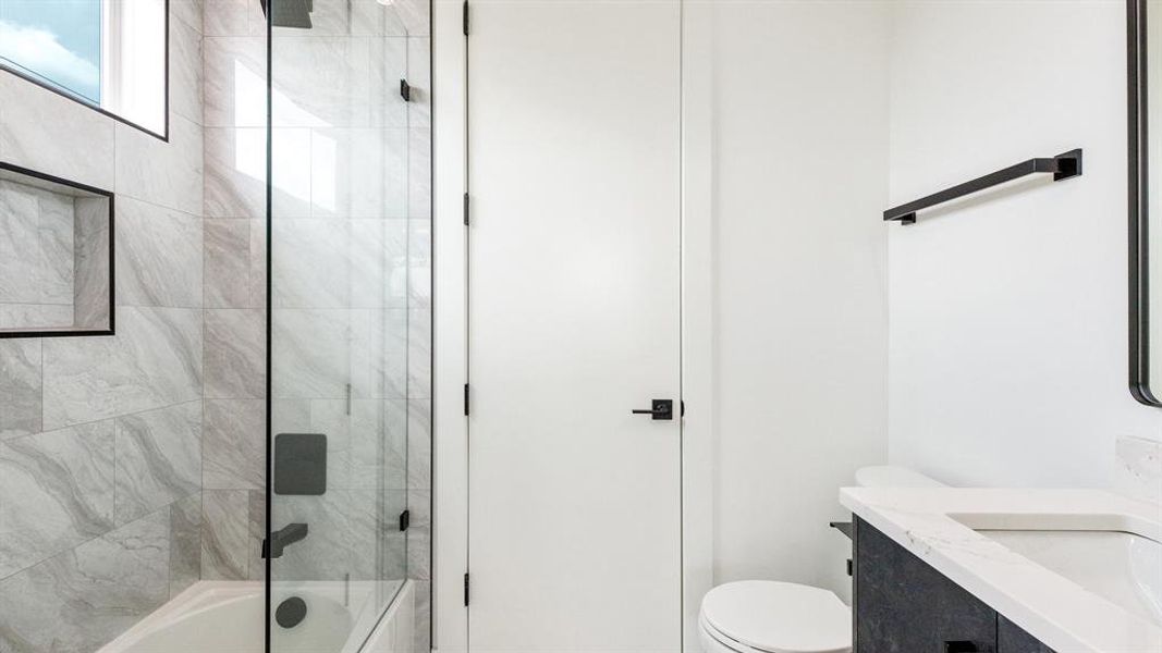 Full bathroom featuring vanity, toilet, and shower / bath combination with glass door