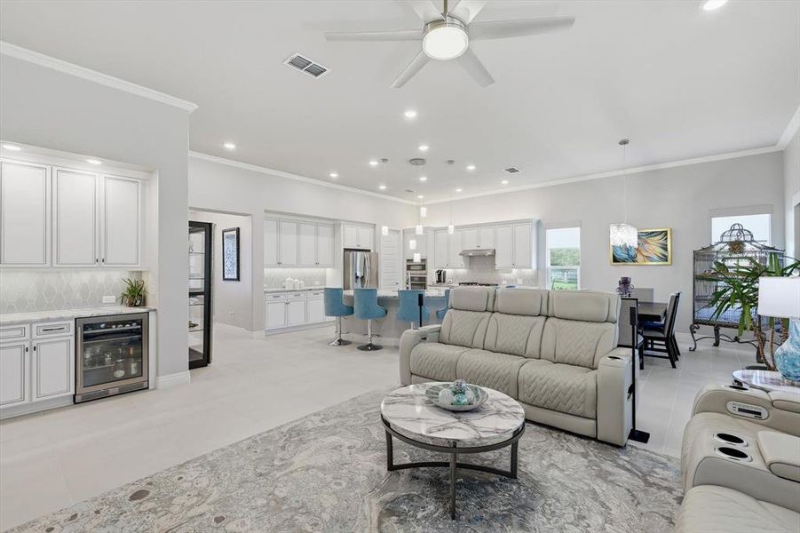 Open-concept living area with light tile flooring and crown molding