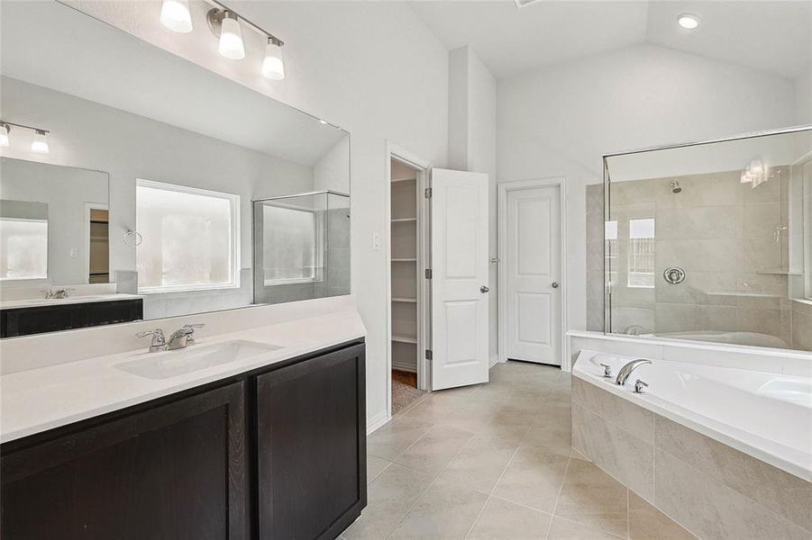 Bathroom with lofted ceiling, vanity, independent shower and bath, tile patterned floors, and a healthy amount of sunlight