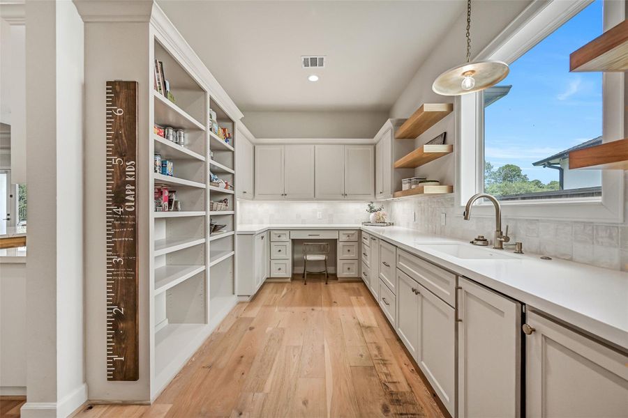 Hidden behind the main cooking wall, an incredible prep kitchen offers extensive cabinetry & open shelving, a second sink, dual dishwashers, ice maker, generous counter space and convenient access from both ends of the main kitchen.