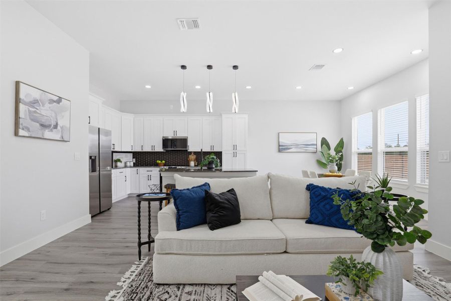 Open-concept living area featuring wood-finish flooring, recessed lighting, and ample natural light through multiple windows