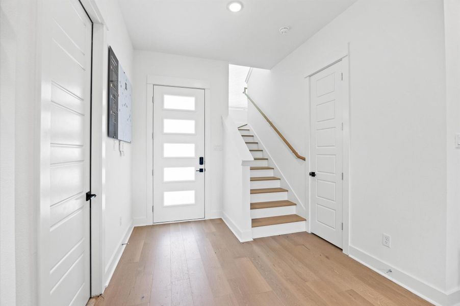 An elegant front door and staircase welcomes you into this stunning home, featuring rich hardwood steps and wooden railing. Natural light pours in from the big window located in the stair landing, illuminating the open layout.