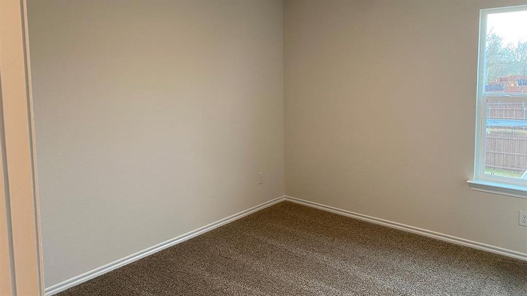 Spare room featuring baseboards and dark carpet
