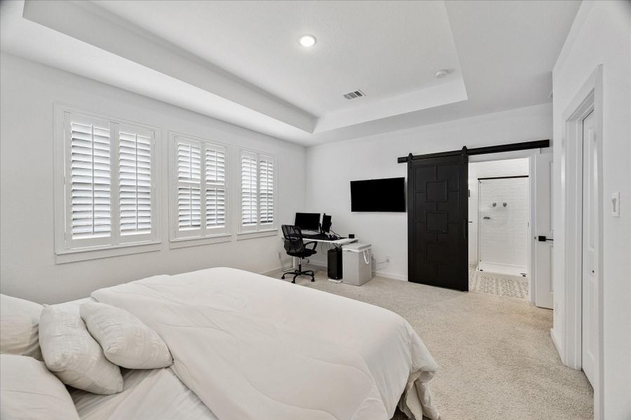 The oversized primary bedroom offers a calm, airy feel with elevated ceiling detail and a thoughtfully designed layout.