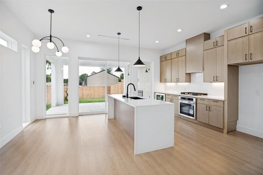 Open-concept kitchen featuring wood-finish flooring, white walls, and a large central island with a white countertop and dark basin sink