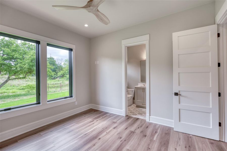 Unfurnished bedroom with light wood-style flooring, baseboards, ensuite bathroom, recessed lighting, and ceiling fan