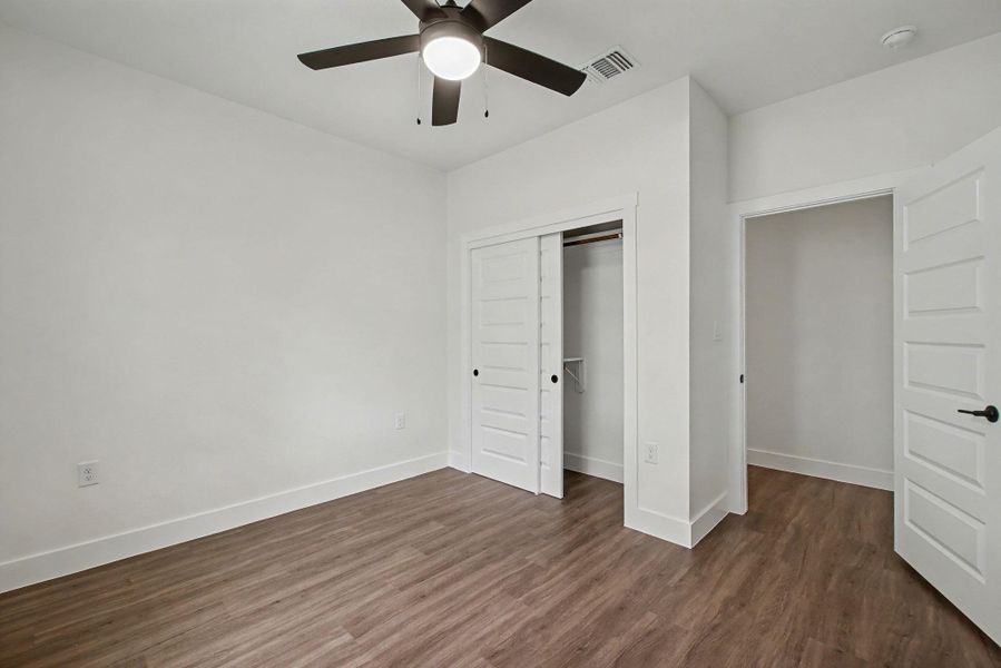 Unfurnished bedroom featuring dark wood finished floors, a closet, and ceiling fan