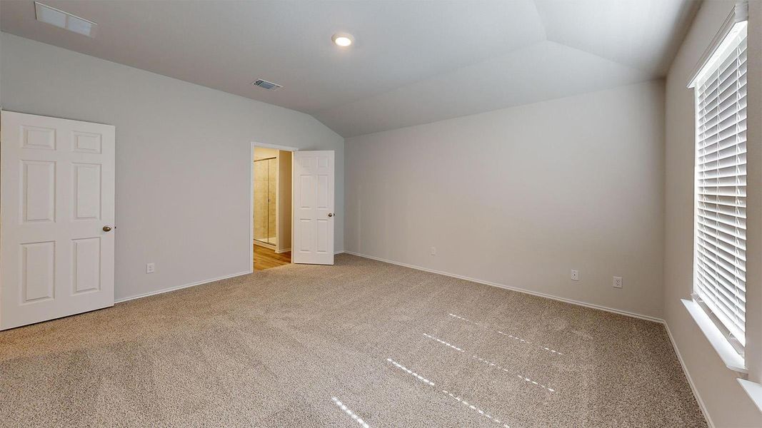 Unfurnished bedroom featuring vaulted ceiling and light carpet