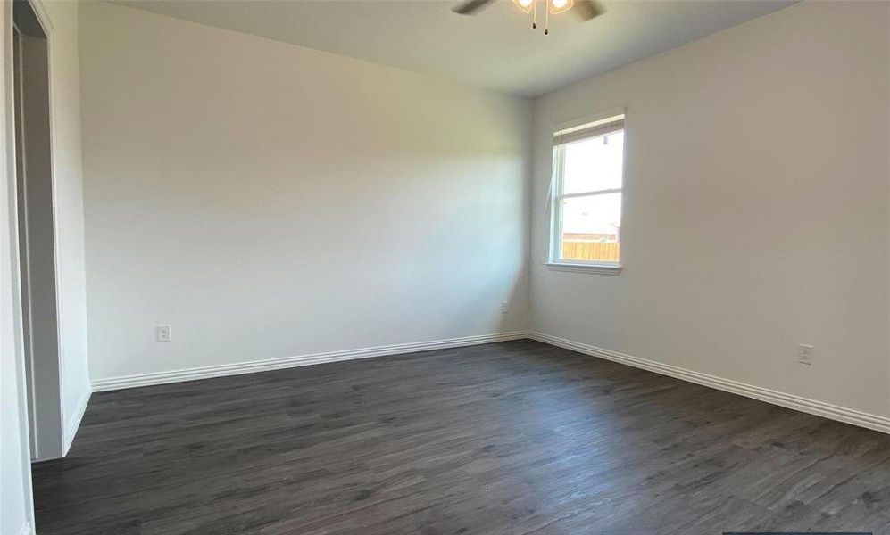 Empty room with ceiling fan and dark wood-type flooring