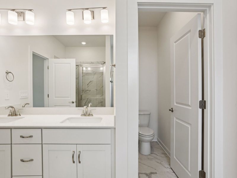 The primary bathroom offers dual vanity sinks and a walk-in shower.