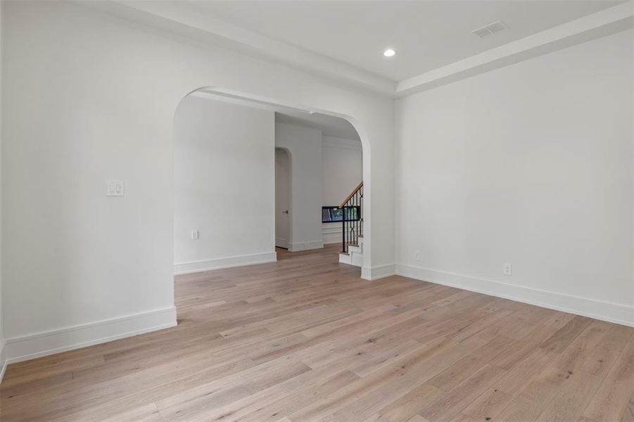 Spare room with stairs, light wood finished floors, arched walkways, and recessed lighting Spare room with stairs, light wood finished floors, arched walkways, and recessed lighting