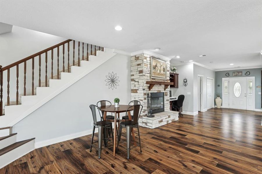 Dining area with ornamental molding, a stone fireplace, and dark hardwood / wood-style floors