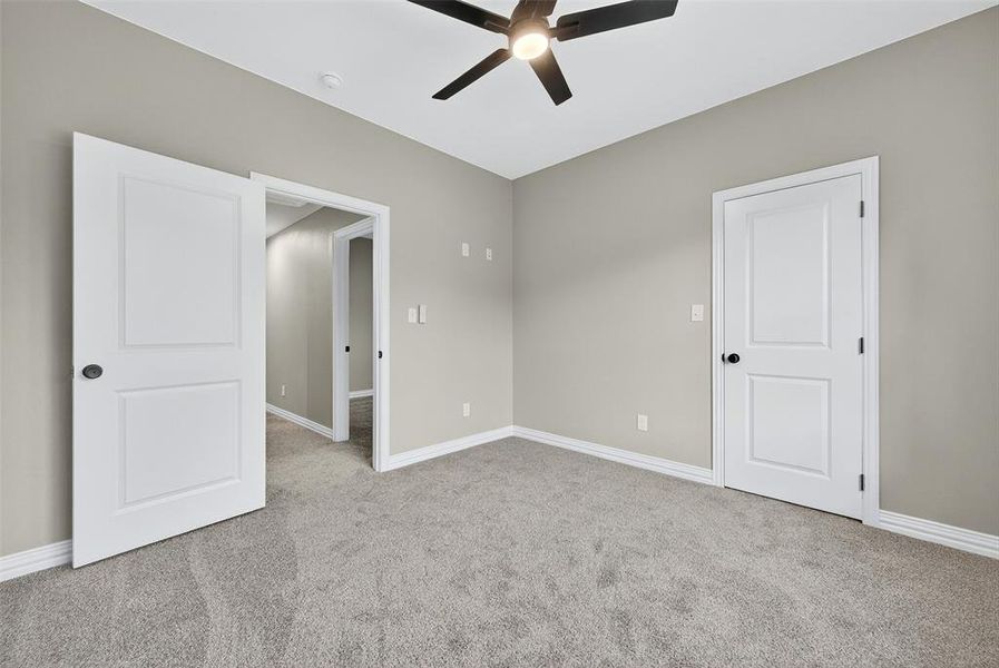 Unfurnished bedroom featuring light colored carpet and a ceiling fan Unfurnished bedroom featuring light colored carpet and a ceiling fan