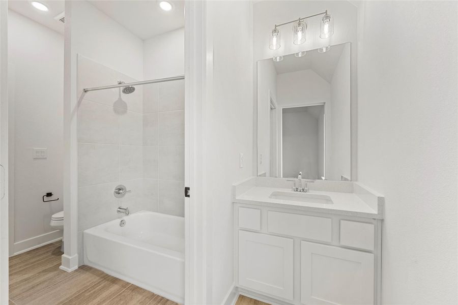 Bathroom with vanity, bathing tub / shower combination, and wood finished floors