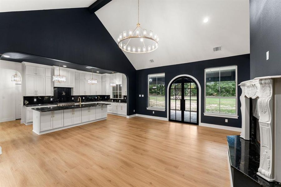 Kitchen with a chandelier, pendant lighting, a center island with sink, light wood-type flooring, and open floor plan