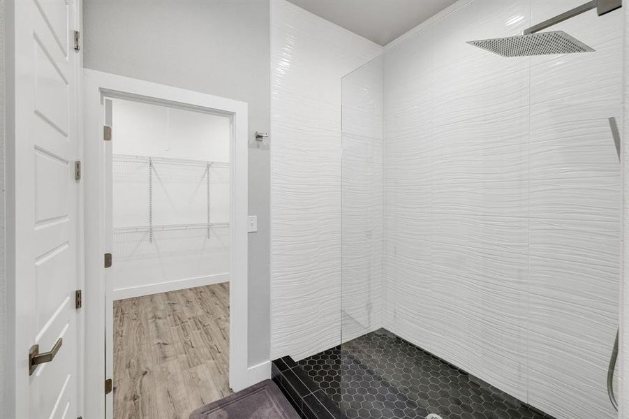 Bathroom with a walk in closet, walk in shower, and light wood finished floors
