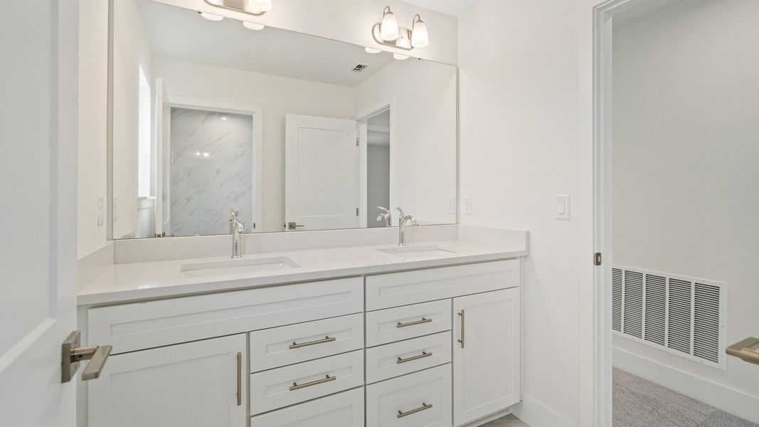 The Sweetgum secondary bathroom with dual sinks upstairs in Trailside at Mount Dora by DRB Homes