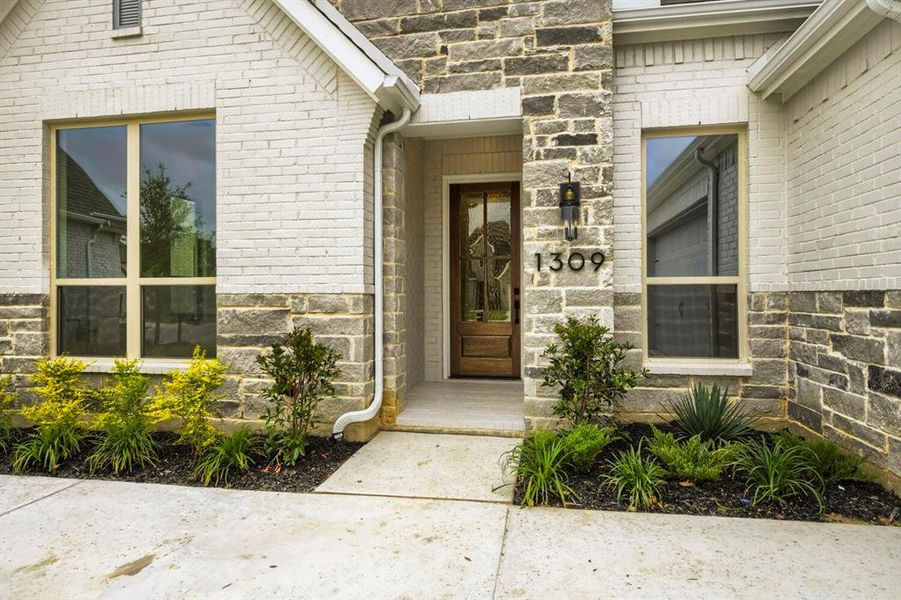 The property features an appealing exterior facade with a combination of light-colored brick and natural stone