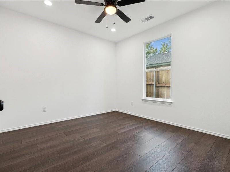 Empty room with ceiling fan and dark hardwood / wood-style flooring