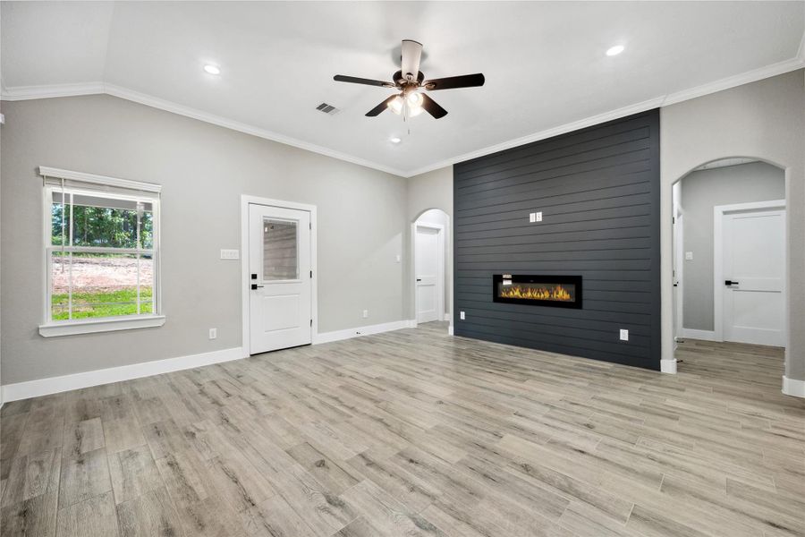 Spacious living room features a beautiful accent wall with electric fireplace. Split bedroom plan with door to right leading to guest bedrooms and door to left leading to Primary suite.