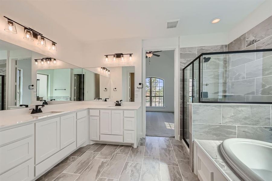 Primary bathroom featuring ceiling fan, separate shower and tub, tile patterned floors, and double vanity