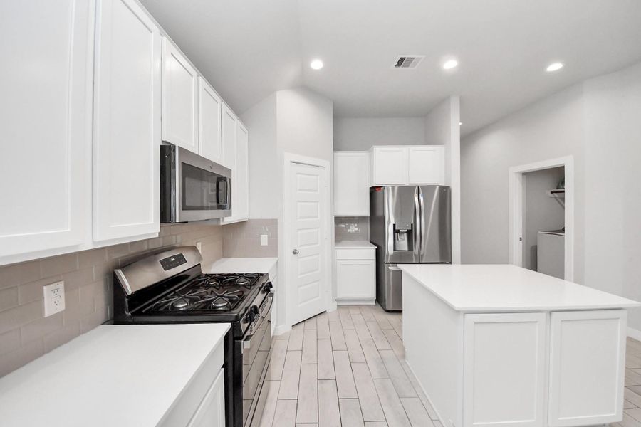 Equipped with a gas range and built-in microwave, this kitchen offers modern functionality along with ample counter space and a spacious center island.