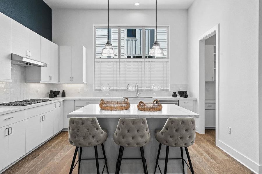 Kitchen with a breakfast bar area, light wood-type flooring, decorative backsplash, white cabinets, and a center island