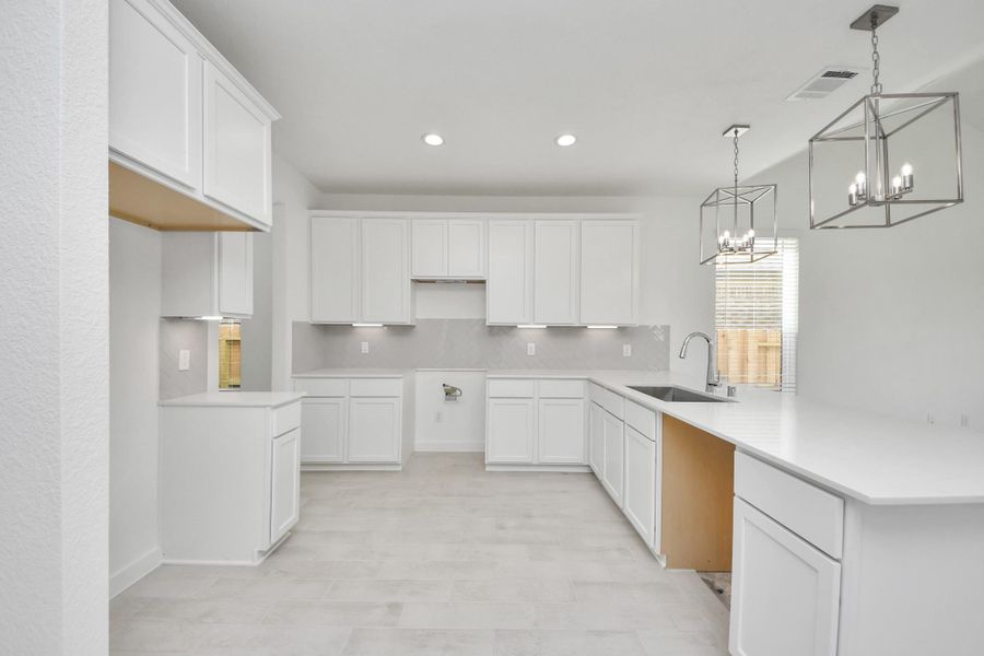 This kitchen is truly a chef's dream! This haven Boasts high ceilings, recessed & pendant lighting, stained wood cabinets, granite countertops, stainless steel appliances, a modern tile backsplash.  All of this overlooks your expansive family room, creating a perfect space for culinary delights and family gatherings.