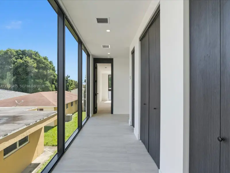 Floor-to-ceiling windows, neutral tile flooring, recessed lighting, and full-height dark-toned cabinetry Floor-to-ceiling windows, neutral tile flooring, recessed lighting, and full-height dark-toned cabinetry