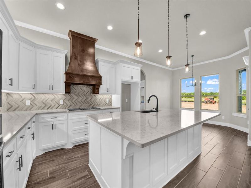 Kitchen featuring light stone counters, white cabinetry, ornamental molding, backsplash, and wood tiled floors Kitchen featuring light stone counters, white cabinetry, ornamental molding, backsplash, and wood tiled floors