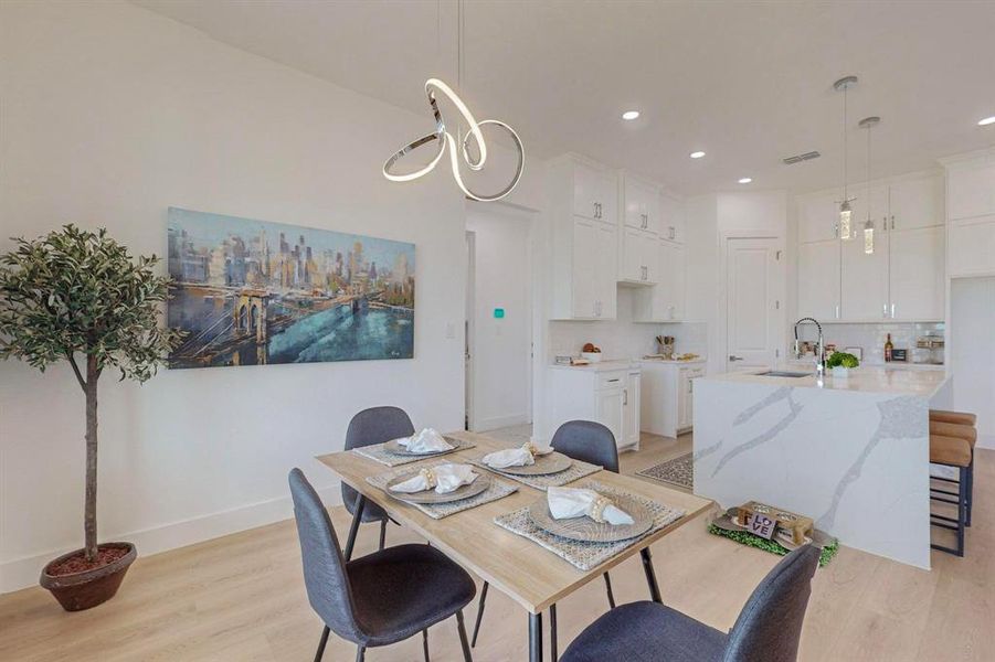 Dining space featuring sink, light wood-type flooring, and a chandelier