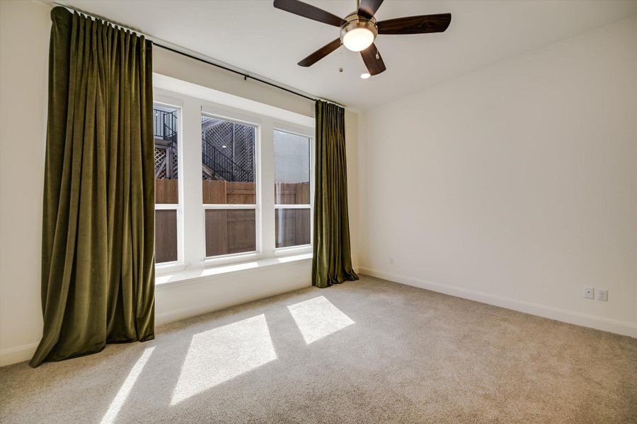 Carpeted empty room with a ceiling fan and baseboards Carpeted empty room with a ceiling fan and baseboards