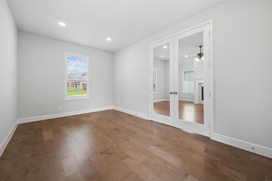 Private office or flex space with hardwood  flooring, recessed lighting, glass French doors, and multiple windows flooding the room with natural light.